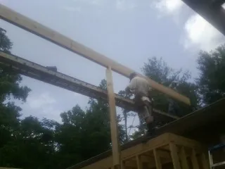 Carpenter setting a ridge beam over a new addition frame — Ice Dam Removal by Roofing Brothers in East Syracuse
