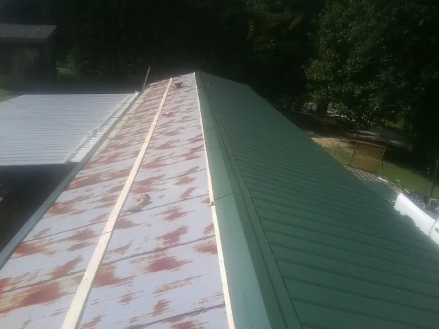 Old rusted panels beside newly installed green metal roofing — Wind Damage Roof Repair by Roofing Brothers in East Syracuse