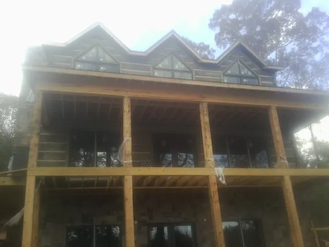 Dormers and porch framing on a large log home under construction — Roof Coating work by our crew in East Syracuse