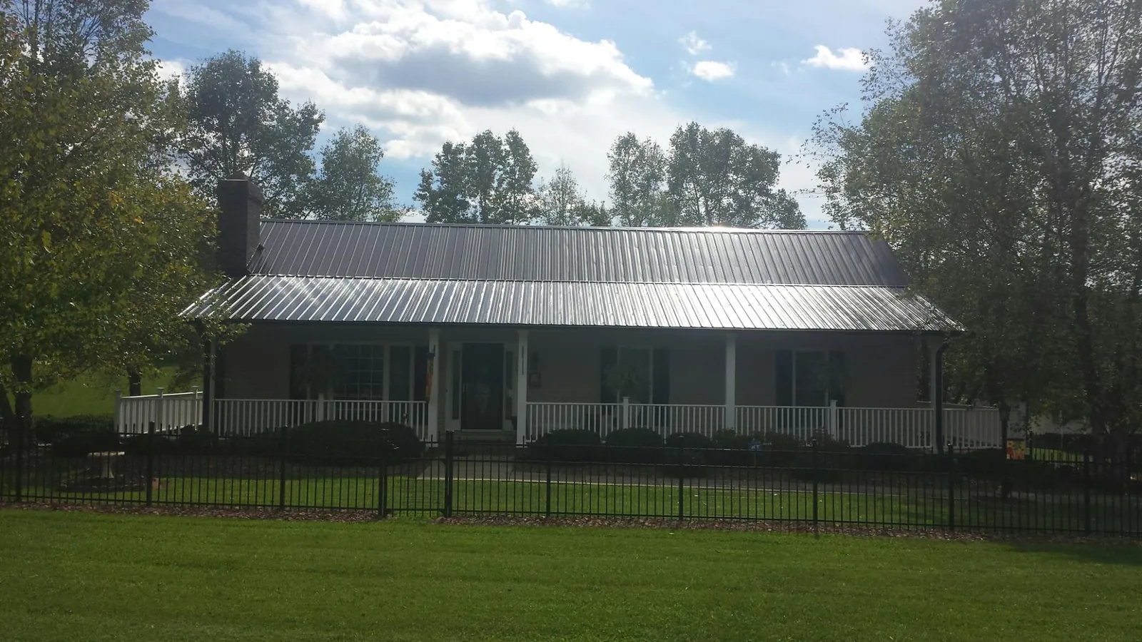 Gray metal roof on a brick ranch with a full width front porch — Gutter Guard Installation work by our crew in East Syracuse