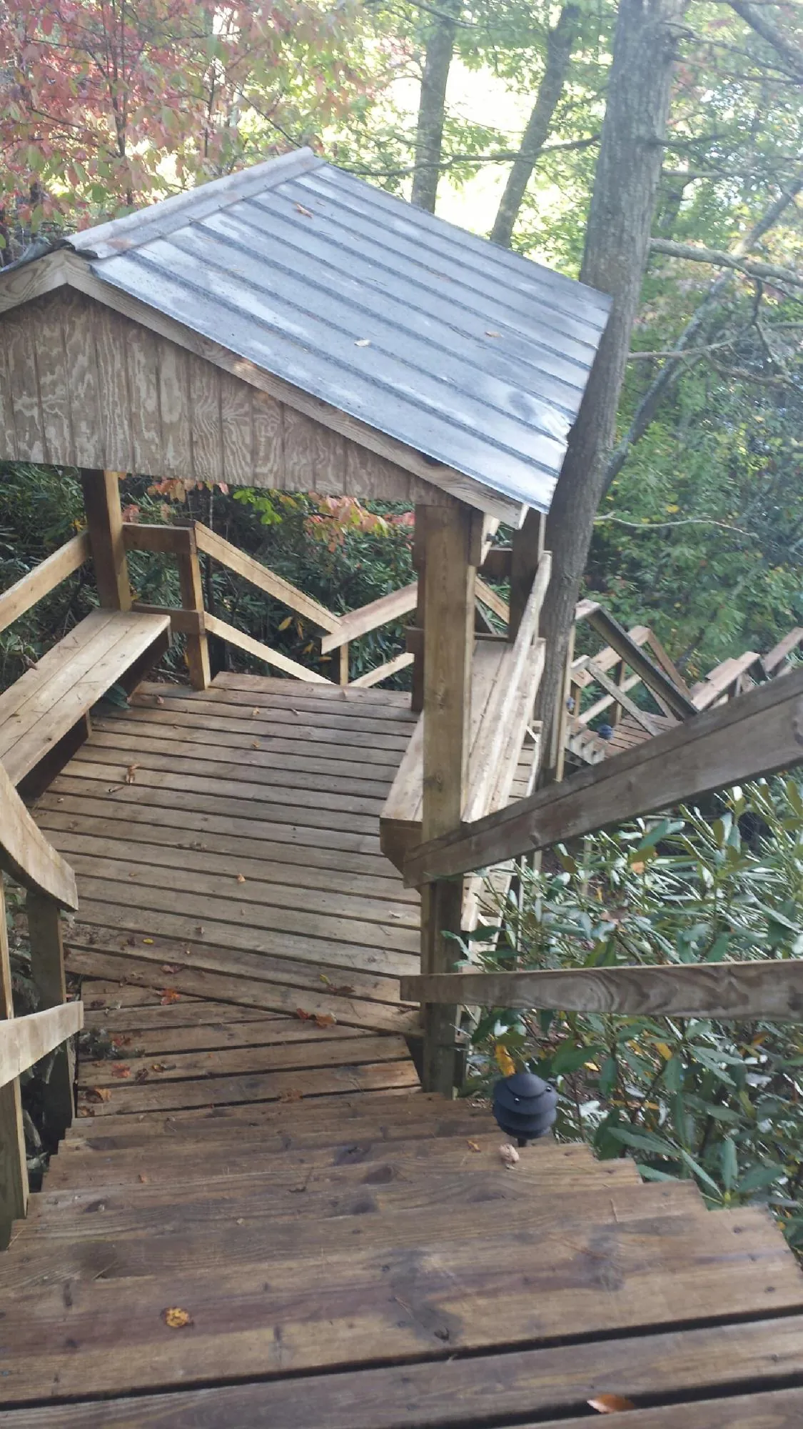 Metal roofed shelter over wooden steps on a wooded walkway — Skylight Repair & Installation work by our crew in East Syracuse